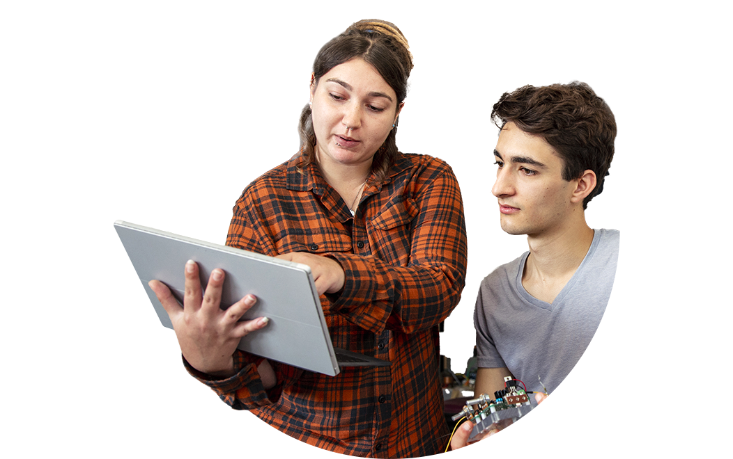 Two people collaborate, with one showing something on a tablet while the other listens and holds an electronic device.