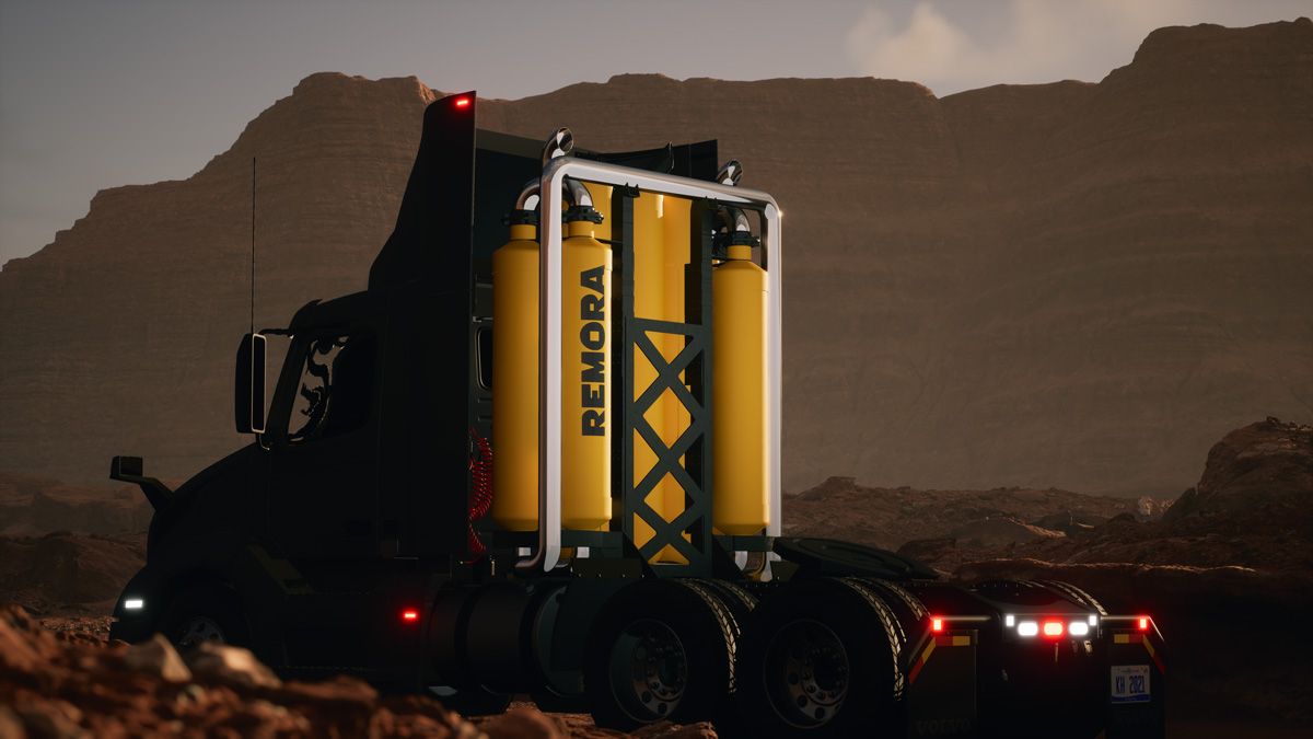 Truck cab driving by mountains without a trailer attached. Four tall tanks are attached to the back of the cab.