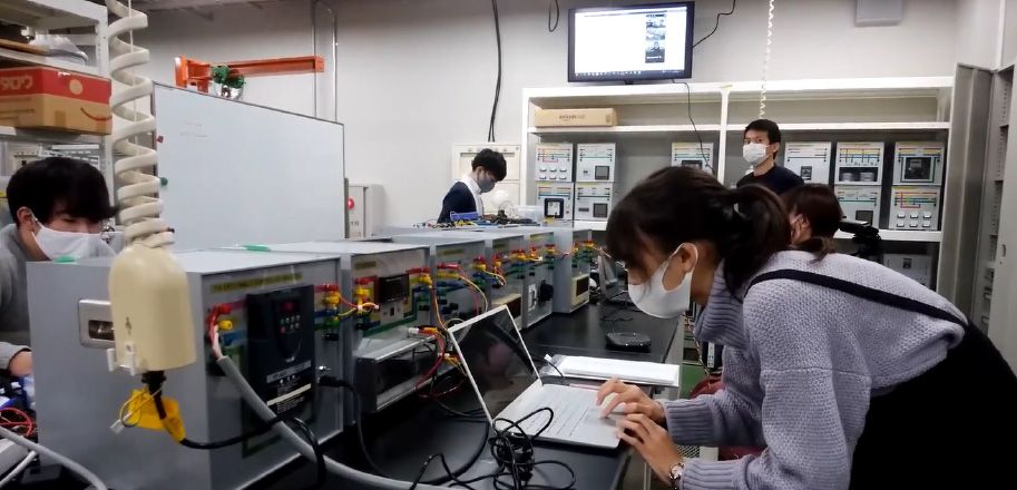 Several students in a lab working on the controller for a synchronous generator.